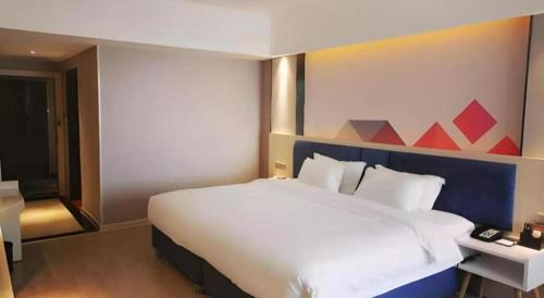 a bedroom with a large white bed with a red painting on the wall at Borrman Hotel Liuzhou High-Speed Railway Station in Liuzhou