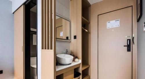 a small bathroom with a sink and a door at GEM Hotel Changzhou Xuejia'aoyuan North High-Speed Railway Station in Changzhou