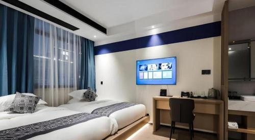 a bedroom with two beds and a desk and a tv at GEM Hotel Changzhou Xuejia'aoyuan North High-Speed Railway Station in Changzhou