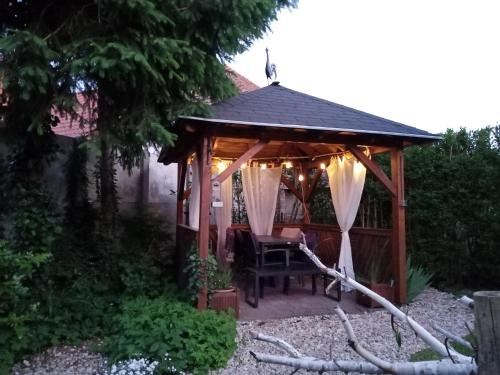 a gazebo with a table and chair in a garden at Kőszeghegyalja Vendégház in Horvátzsidány