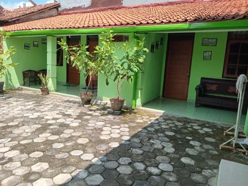 a green house with potted trees in front of it at Omah 365 Homestay in Sentool