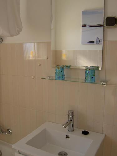 a white bathroom with a sink and a mirror at Quartos Com Boas Vistas in Ribeira da Gafa