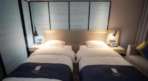 two beds in a room with a headboard and sidx sidx sidx sidx at Echarm Hotel Changsha Wuyi Square Xiangya Affiliated 1st Provincial Maternity and Child in Changsha