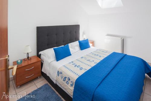 a bedroom with a large bed with blue pillows at Apartments Jerko in Primošten