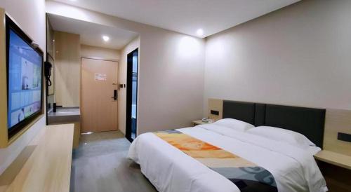 a bedroom with a large bed and a flat screen tv at Shell Hotel Wuxi Huishan District Chang'an Town in Wuxi