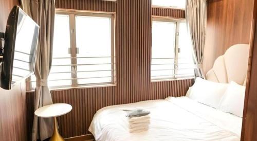 a small room with a bed and two windows at Sunny Day Hotel in Hong Kong