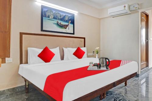 a bedroom with a large bed with red pillows at Hotel O Poptavern Premium in Trivandrum