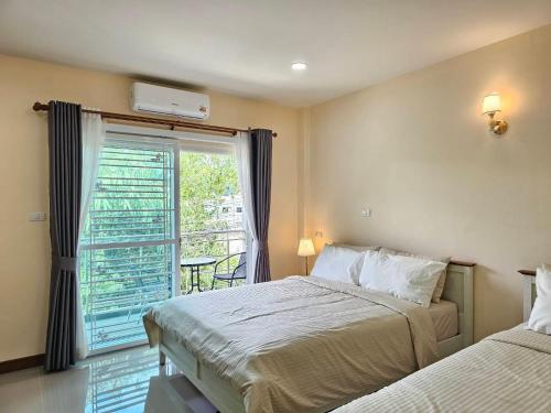 a bedroom with two beds and a window with a balcony at Hatyai Luxe Stay in Hat Yai