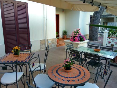 a patio with two tables and chairs and flowers at Le Camelie in Ginosa Marina