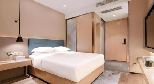 a bedroom with a large white bed and a bathroom at ZMAX Hotels Shenzhen Lianhuacun Metro Station in Shenzhen