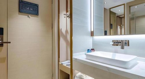 a bathroom with a white sink and a mirror at Lavande Hotel Shenzhen East Gate Wanxiang City Guomao Metro Statipn in Shenzhen