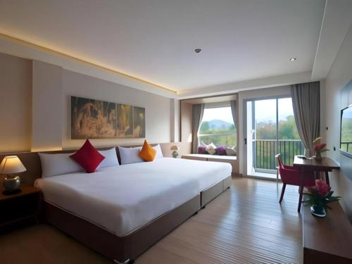 a bedroom with a large white bed and a large window at River Kwai Village Hotel in Ban Kaeng Raboet