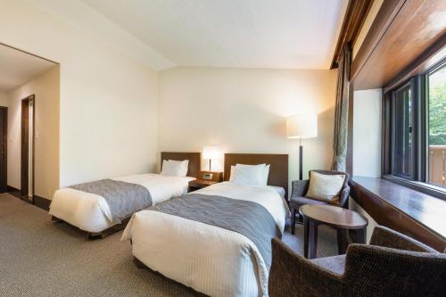 a hotel room with two beds and a chair at Yatsugatake Kogen Lodge in Minamimaki
