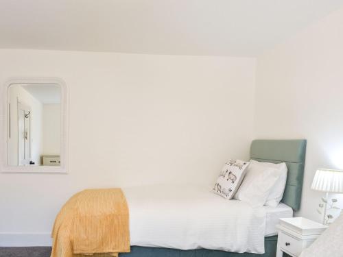 a white bedroom with a bed and a mirror at The Croft in Stanhope