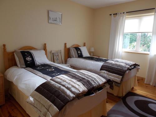 2 camas en una habitación con ventana en Reads Park Self - Catering Accommodation en Galbally