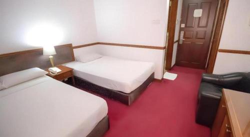 a hotel room with two beds and a chair at Four Chain View Hotel in Singapore