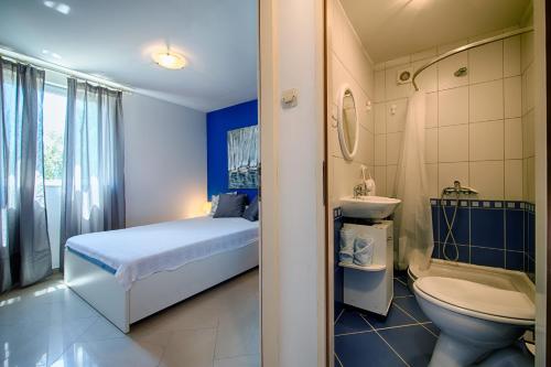 a bathroom with a bed and a toilet and a sink at Apartments Perla in Rukavac