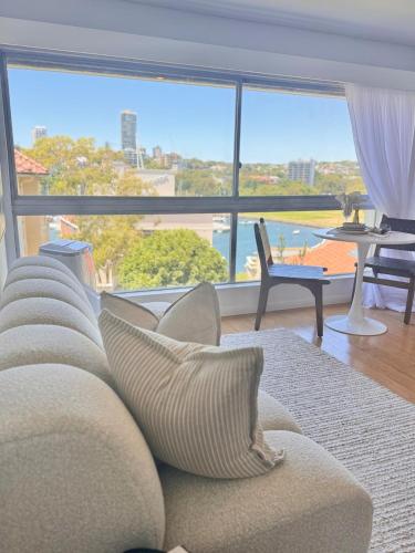 a living room with a couch and a large window at Harbour View Apt with Rooftop Pool in Sydney