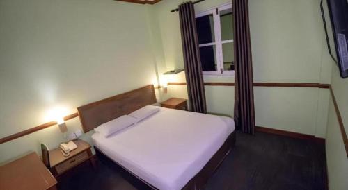 a bedroom with a large white bed with a window at Four Chain View Hotel in Singapore