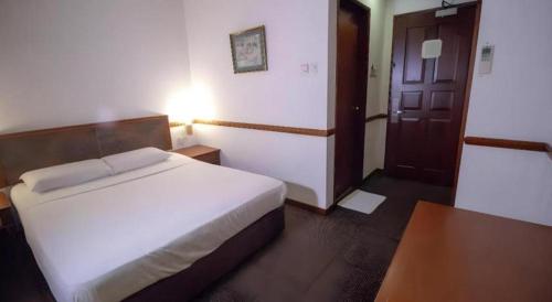 a bedroom with a white bed and a wooden door at Four Chain View Hotel in Singapore