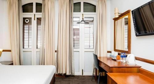 a hotel room with a bed and a desk and a bed and mirror at Four Chain View Hotel in Singapore