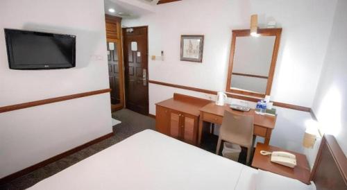 a room with a bed and a desk and a television at Four Chain View Hotel in Singapore