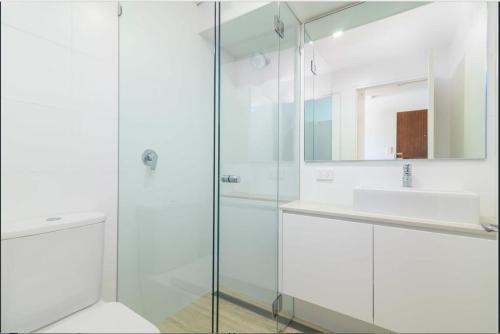 a bathroom with a glass shower and a sink at Harbour View Apt with Rooftop Pool in Sydney