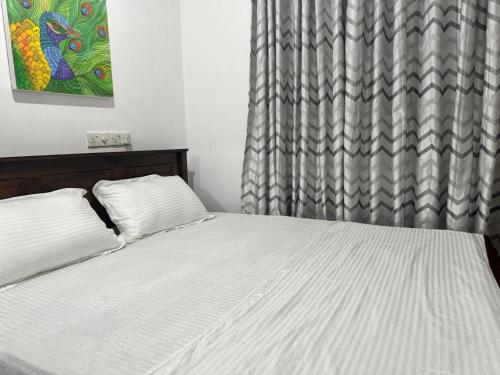 1 dormitorio con cama blanca y cortina en Three M Mirissa, en Mirissa