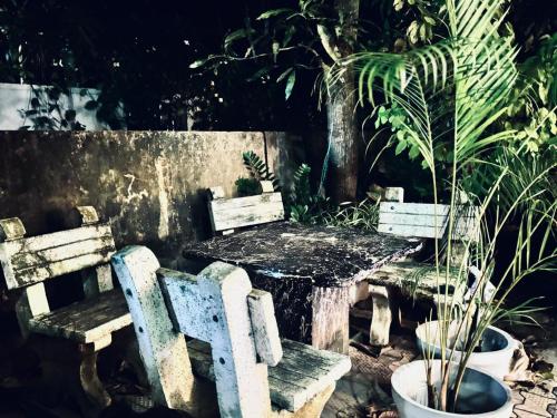 a wooden table and two chairs with a table and plants at Three M Mirissa in Mirissa