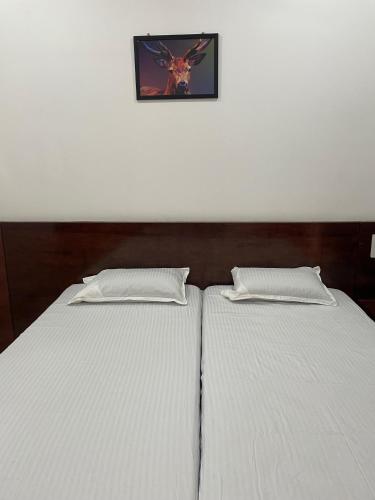 two beds in a bedroom with a picture on the wall at Vengilate Sree Muthappan Residency in Parassinikadavu