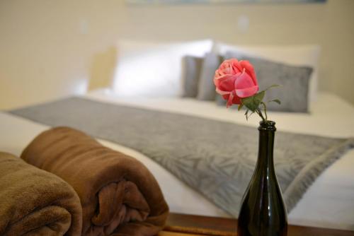 a rose in a vase on a table next to a bed at Oasis Tajaja Pousada in Jacumã