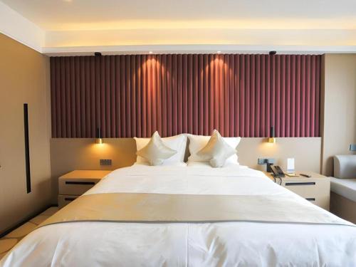 a large white bed in a bedroom with red curtains at Yanji Yanbian International Hotel in Yanji