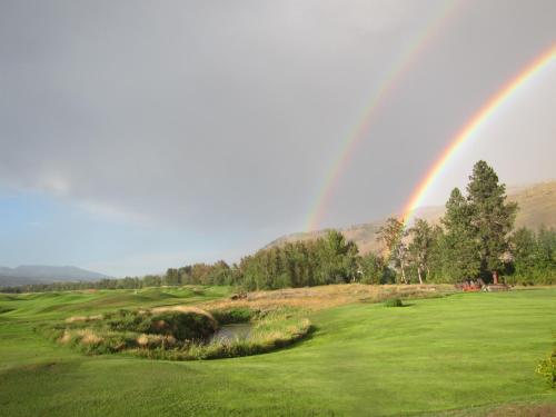 a rainbow over a golf course with a green at Overlander B&B in Kamloops