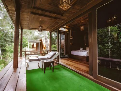 Ban Pha Saeng LangRiver View Resort At Chaewlan的卧室的木质露台上铺着绿色地毯