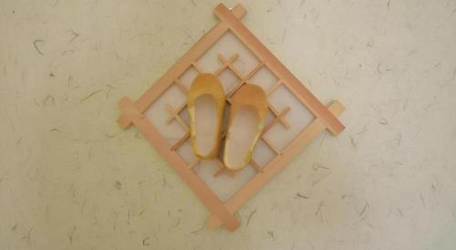 a pair of gold shoes hanging on a wall at Nabijam Hanok Hotel in Jeonju