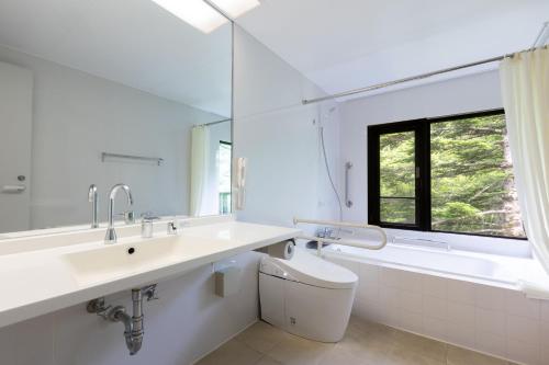 a bathroom with a sink and a toilet and a tub at Yatsugatake Kogen Lodge in Minamimaki