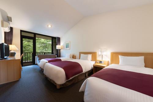 a hotel room with two beds and a television at Yatsugatake Kogen Lodge in Minamimaki