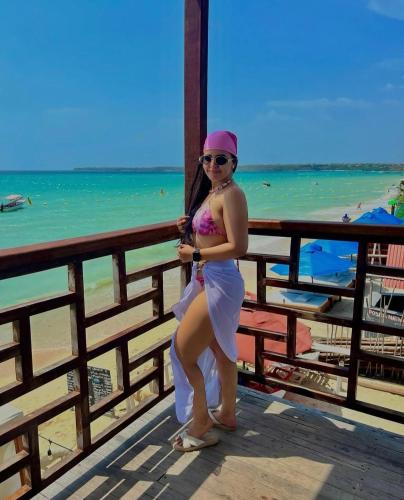 a woman in a white dress standing next to the beach at Roma beach in Cartagena de Indias