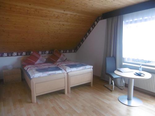 a bedroom with a bed and a table and a window at Haus Hochwaldhöhe in Morbach