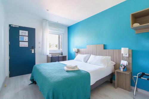 a bedroom with a large bed with a blue wall at Brit Hotel Confort Manosque Cadarache in Manosque