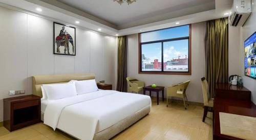 a hotel room with a white bed and a desk at Jian Guo Grand Hotel in Vientiane