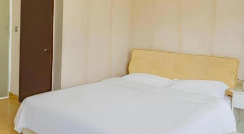 a white bed with two pillows in a room at Jian Guo Grand Hotel in Vientiane