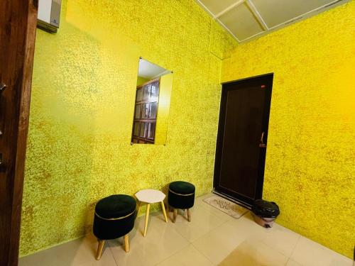 a yellow room with a table and two stools at Serene Stays in Jorhat
