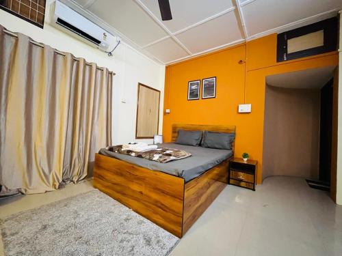 ein Schlafzimmer mit einem Bett mit einer orangefarbenen Wand in der Unterkunft Serene Stays in Jorhat