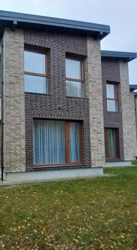 a brick house with three windows and a grass field at Baltašiške in Druskininkai