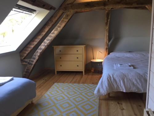 a bedroom with a bed and a dresser in a attic at La Maison d'Artiste à 5 min du Haras du Pin, Normandie in Ginia
