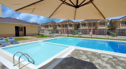 a swimming pool with an umbrella next to a house at Regal Suites in Athi River