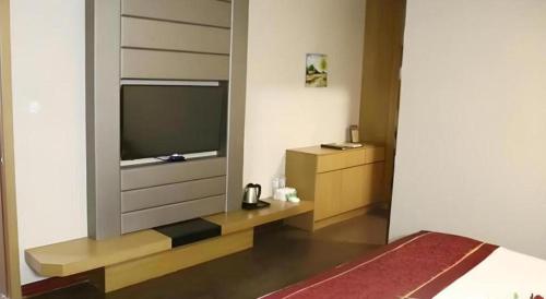 a bedroom with a tv and a bed in a room at GreenTree Inn Gaoyou Government in Yangzhou