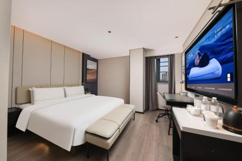 a bedroom with a large white bed and a flat screen tv at Atour Hotel People's Square Metro Station Shanghai in Shanghai