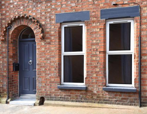 a brick building with a blue door and two windows at Ocho Homes by Eight Continents in Belfast